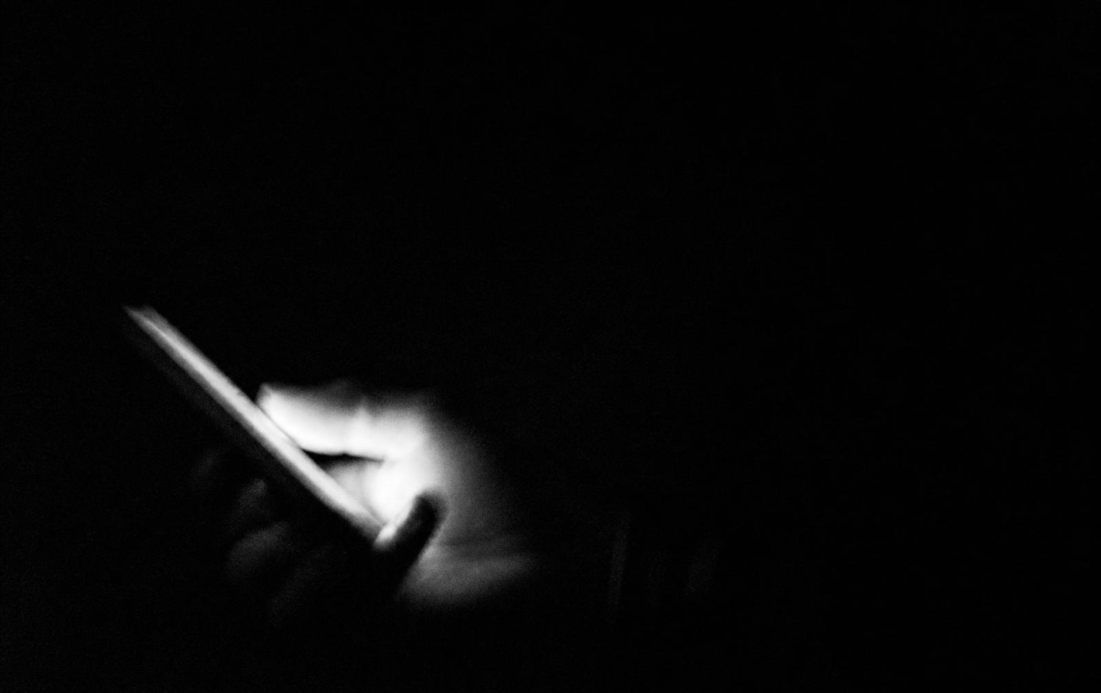 Dłonie trzymające telefon przy stole